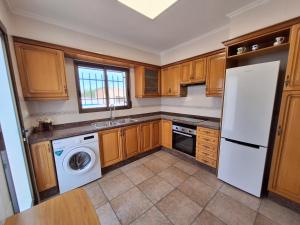 a kitchen with wooden cabinets and a washer and dryer at Villa cerca de Valencia con piscina junto a la montaña in Vilamarxant