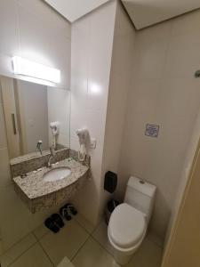 a bathroom with a toilet and a sink and a mirror at Velit Prime Motel in Erechim +5 photos