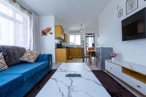 a living room with a blue couch and a kitchen at Serene Retreat 2 Bedroom with Pool, Netflix Fast Wifi and Gym in Nairobi