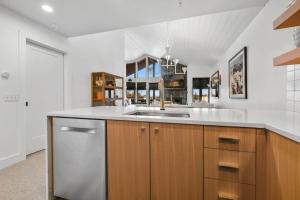 cocina con armarios de madera y fregadero de acero inoxidable en Exceptional Village Watch Condo, en Stratton