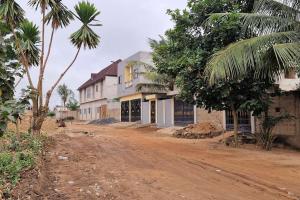 a dirt road in front of a house with trees at Appart Chambre Salon meublé in Madjikpéto