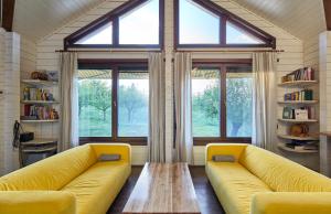 a living room with a yellow couch and a large window at Dream House - Buzau Valley in Vipereşti