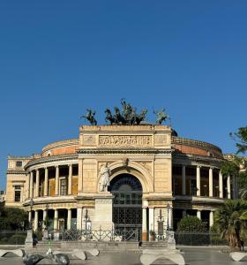 un grand bâtiment avec une statue au-dessus dans l'établissement City Room, à Palerme