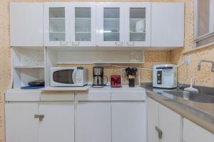 Una cocina blanca con gabinetes y electrodomésticos blancos. en 3Hab Conforto: 100m de la Playa Copacabana-Ipanema, en Río de Janeiro