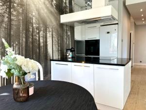 a kitchen with white cabinets and a table with a vase of flowers at Apartament La Bella klimatyzacja, garaż podziemny, Fv in Suwałki