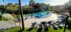 a pool with chaise lounge chairs and a palm tree at The Blue Diamond Villa-25min to Valencia in Turís