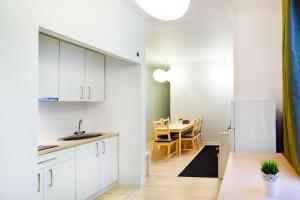 a kitchen and dining room with white cabinets and a table at Lote Apartment in Rīga