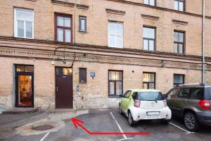 two cars parked in a parking lot in front of a brick building at Lote Apartment in Rīga