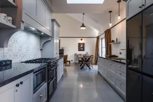 une grande cuisine avec des armoires blanches et une table dans l'établissement Black Stilt Cottage, luxury stay in Twizel, à Twizel 14 autres photos