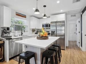 eine Küche mit einer großen weißen Insel mit schwarzen Hockern in der Unterkunft Coastal Hideaway in Lake Worth + 14 Fotos