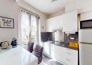 Una cocina blanca con gabinetes blancos y una ventana. en Cozy APT in Le Perreux with Parisian Charm & Disneyland Fun, en Le Perreux-Sur-Marne