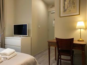 a room with a bed and a desk with a television at Hotel Saint Yves in Nantes