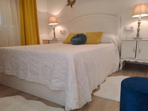 ein Schlafzimmer mit einem weißen Bett und gelben Kissen in der Unterkunft Casa Romero Garden in Vilanova de Arousa