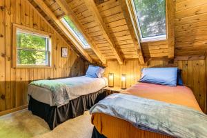 two beds in a room with wooden walls and windows at Hot Tub and Fire Pit Cozy Cabin in Maggie Valley in Maggie Valley