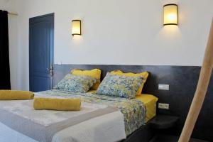 a bedroom with two beds with yellow sheets and blue pillows at Villa Sarah - Piscine chauffée in Sidi Kaouki