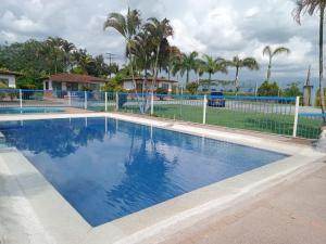 a large swimming pool with a fence and palm trees at Hotel campestre manantial del Quindio in Montenegro