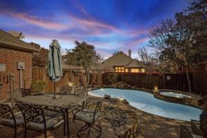 un patio con mesa, sombrilla y piscina en Dream Vacay in Central Plano - Pool & Grill, en Plano