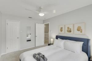 a white bedroom with a large bed with a blue headboard at Perfect Getaway Home w 5 Bedrooms & Backyard Oasis in Plano +37 photos