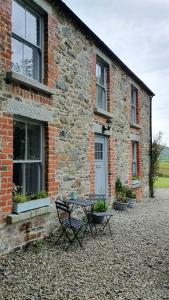 un bâtiment en briques avec une table devant lui dans l'établissement Whitehill Cottage, à Castlewellan
