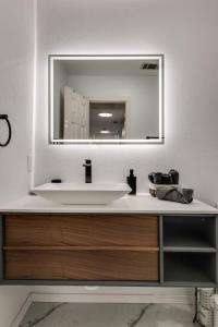 ein Badezimmer mit einem weißen Waschbecken und einem Spiegel in der Unterkunft Modern and Luxury DFW Mansion with Backyard Oasis in Haltom City + 34 Fotos