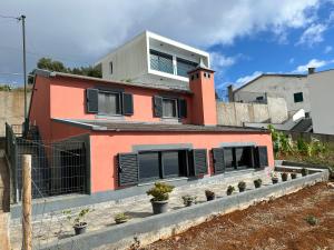 a orange house with black shutters on it at Palheirinho da Achada in Arco da Calheta