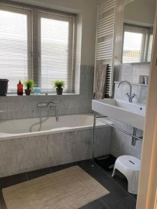a bathroom with a white tub and a sink at Villa Bollenstreek in Hillegom