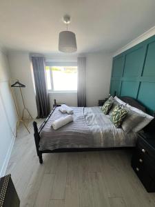 a bedroom with a large bed with a blue headboard at Elro House Holiday Let in Tillicoultry