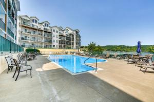 a swimming pool with chairs and a building at Lakefront Camdenton Condo Near Ha Ha Tonka and Golf! in Camdenton