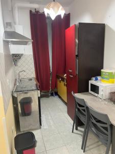 SALENTINI APPARTAMENTo في روما: مطبخ مع دواليب حمراء وطاولة مع ميكروويف +23 صورة
