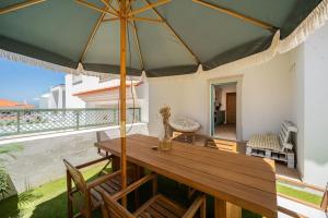 a wooden table with an umbrella on a balcony at Villa Serenity Tapada - Pool, Cinema Room & Gym in Nazaré