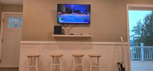 a bar with three stools and a television on a wall at Sparta lakehouse in Sparta +13 photos
