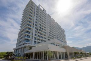 a large white building with palm trees in front of it at Hotel Porto Horizonte All inclusive By OxoHotel in Santa Marta