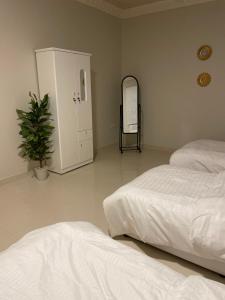 a bedroom with two beds and a mirror and a plant at قرطبه مودرن - قريبة من المطار in Riyadh