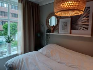 een slaapkamer met een bed, een kroonluchter en een raam bij Ytre Markveien 37 in Bergen