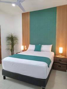 een slaapkamer met een groot bed met een groene muur bij Hotel Punta Colibrí in Puerto Escondido