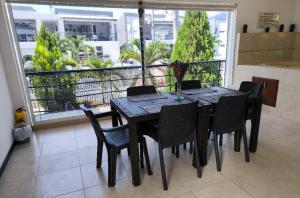a black dining room table with black chairs and a balcony at Apartasol Ciudadela Santafe in Santa Fe de Antioquia