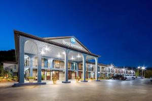 a hotel exterior at night with a parking lot at Best Western Corbin Inn in Corbin