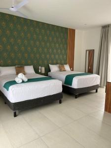 2 bedden in een hotelkamer met groen behang bij Hotel Punta Colibrí in Puerto Escondido