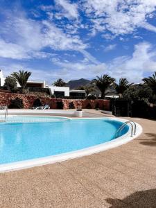 a large swimming pool in a yard with palm trees at Casa Buna Colorada in Playa Blanca