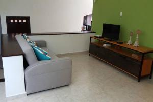 een woonkamer met een bank en een bureau met een televisie bij House completely furnished Total privacy 8Pax in Cancun
