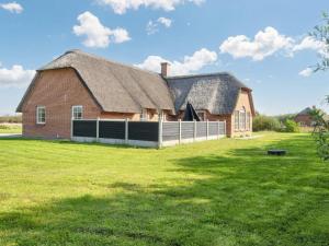 a large red brick barn with a white fence at Luxury Retreat with Pool in Ulfborg