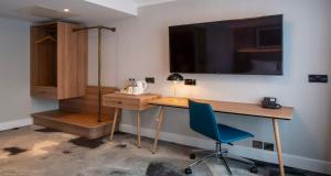 a room with a desk and a chair and a television at London Chigwell Prince Regent Hotel, BW Signature Collection in London
