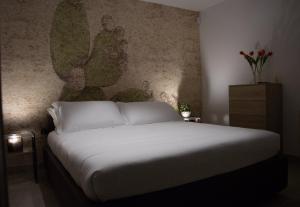 a bedroom with a white bed with a painting on the wall at Martine Dimore Storiche di Puglia in Martina Franca