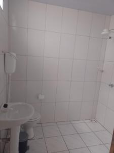 a white bathroom with a toilet and a sink at Hospedagem da Cris in Salvador