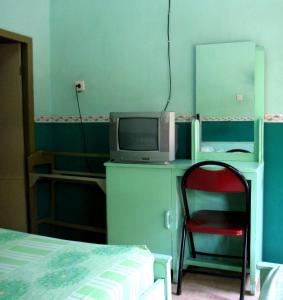 Un dormitorio con una cama, un televisor y una silla. en Hotel Anugerah Bondowoso, en Bondowoso