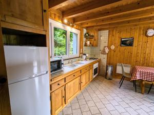 a kitchen with a white refrigerator in a wooden kitchen at Chalet de Montagne Chaleureux avec Cheminée, Terrasse et Proche Ski - FR-1-589-2 in Anould