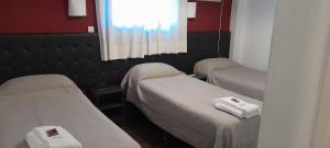 two beds in a hospital room with a window at Hotel Kapac in Mendoza