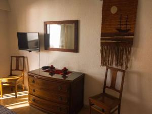a bedroom with a dresser and a television and two chairs at Edificio céntrico en el Este, Torre Gorlero in Punta del Este