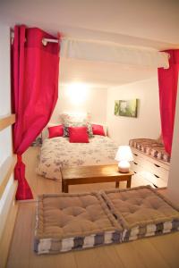 sypialnia z czerwonymi zasłonami, łóżkiem i stołem w obiekcie Le Studio Flore w Paryżu