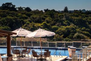 two tables and chairs with umbrellas next to a pool at Master Gramado Hotel - Localização no Centro e Espaço Kids Incrível in Gramado